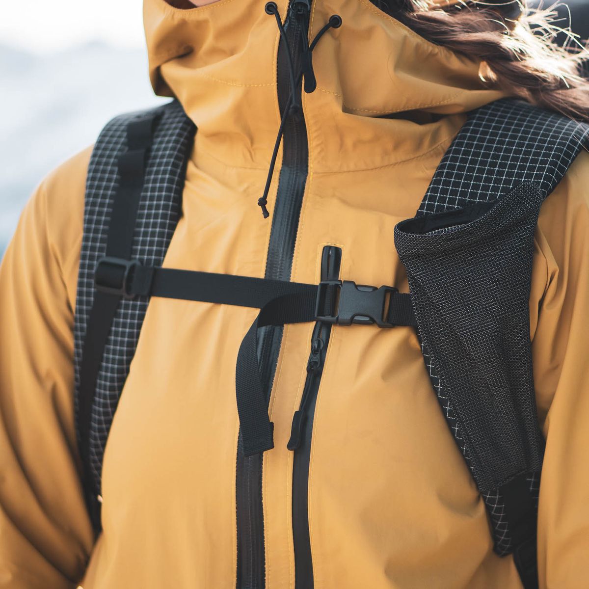 Wanderer in a yellow jacket with a closed chest strap and a bottle pocket on the shoulder strap of the jacket. Agilist